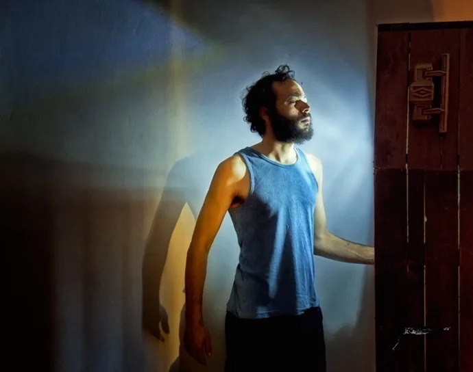 a bearded man in profile, portrayed in blue light,